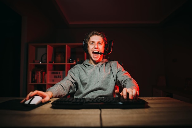 jovem no fone de ouvido jogando videogame com um sorriso no rosto em uma sala com interior vermelho