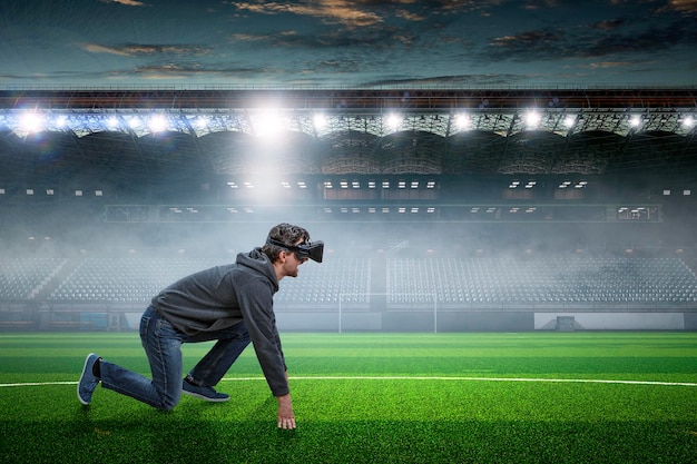 Jovem no fone de ouvido VR na posição pronta para começar em um estádio. Mídia mista