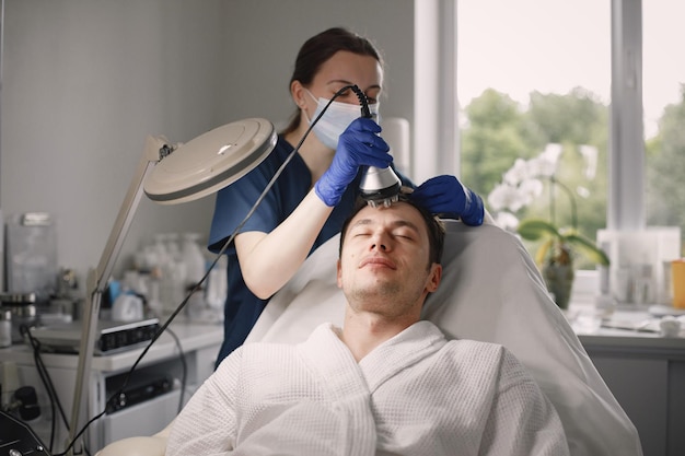 Jovem no gabinete de cosmetologista tem um procedimento facial de cavitação