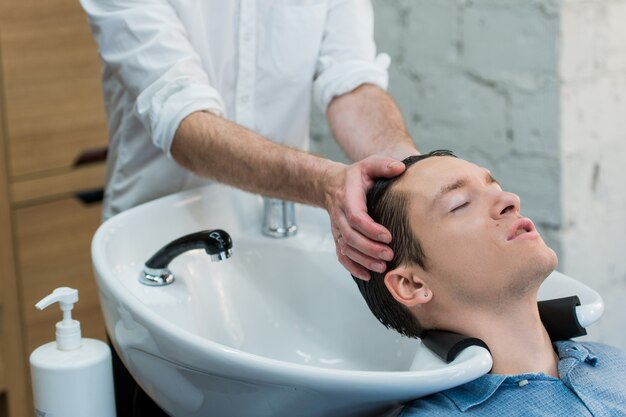 Jovem no salão de cabeleireiro, lavando o cabelo