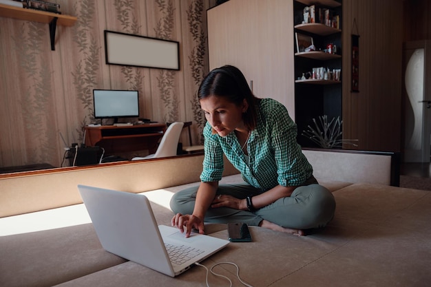 Foto jovem no sofá trabalhando alegremente em um novo projeto com laptop em casa