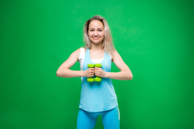 jovem no sportswear segurando halteres em uma parede verde, espaço para texto