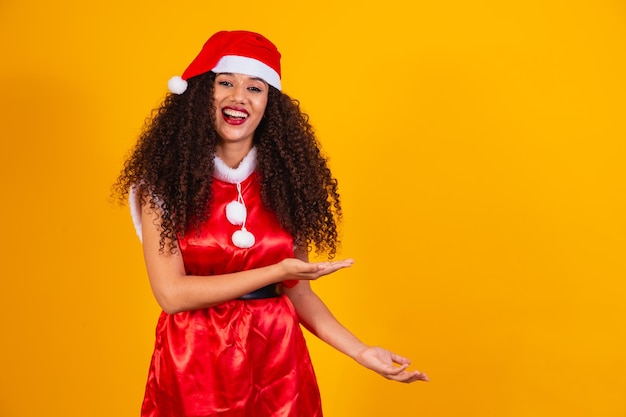 Jovem noelete vestida para o natal, apontando para o espaço livre para texto.