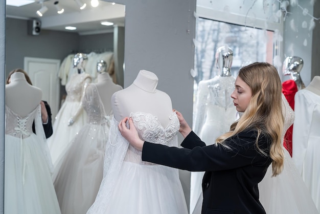 Jovem noiva bonita olhando os melhores vestidos na loja