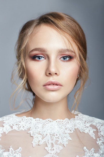 Jovem noiva em um vestido de noiva branco luxuoso e cabelo bonito. mulher antes da cerimônia de casamento, a figura perfeita da noiva, bela maquiagem e penteado