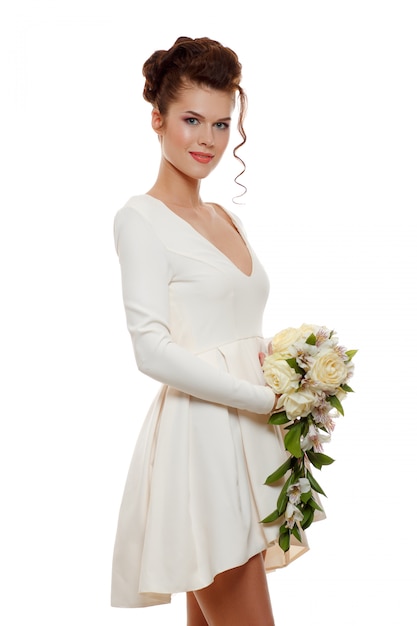 Jovem noiva feliz em vestido curto branco com um buquê de flores