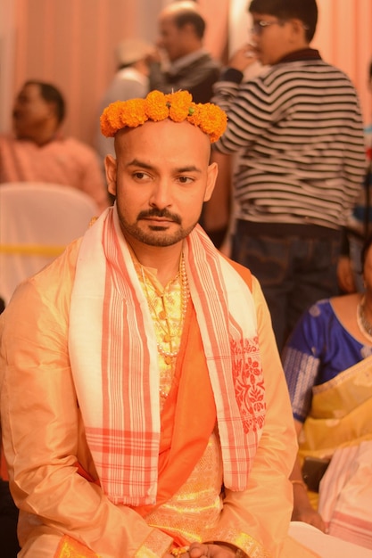 Foto jovem noivo em roupas tradicionais sentado na cerimônia de casamento