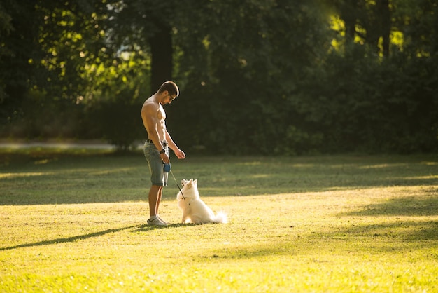 Jovem nu segurando cachorro Spitz alemão no parque juntos apreciando a vista