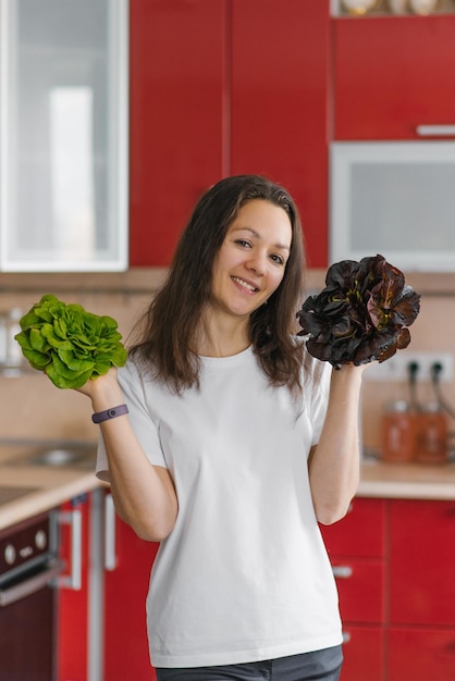 Jovem nutricionista vegetariana feliz tem dois tipos de salada em suas mãos comida orgânica natural comida saudável em casa