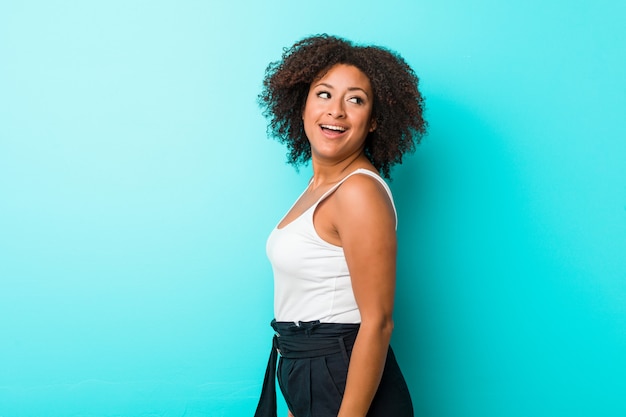 Jovem olha de lado sorrindo, alegre e agradável.