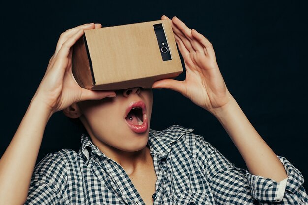 Foto jovem olhando através de um fone de ouvido de papelão de realidade virtual