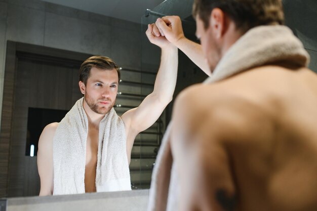 Foto jovem olhando no espelho depois de fazer a barba em casa