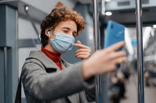 Jovem olhando para a tela de seu smartphone enquanto está em um vagão de metrô