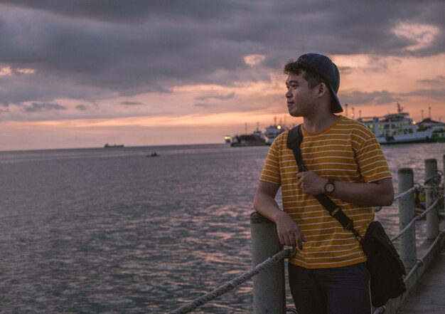 Foto jovem olhando para o mar contra o céu