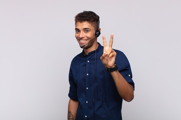 Jovem operador de telemarketing sorrindo e parecendo amigável, mostrando o número dois ou o segundo com a mão para a frente, em contagem regressiva