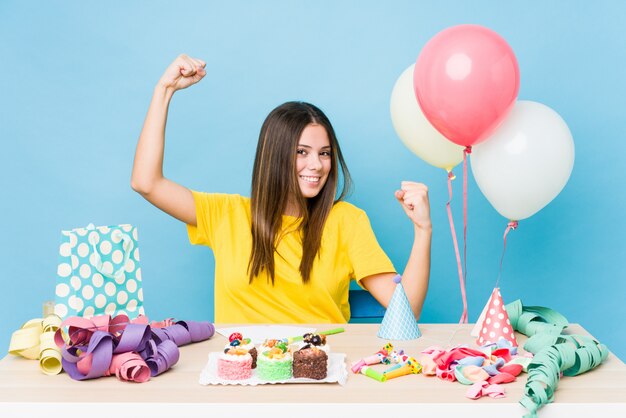 Jovem organizando um aniversário mostrando o gesto de força com os braços, símbolo do poder feminino