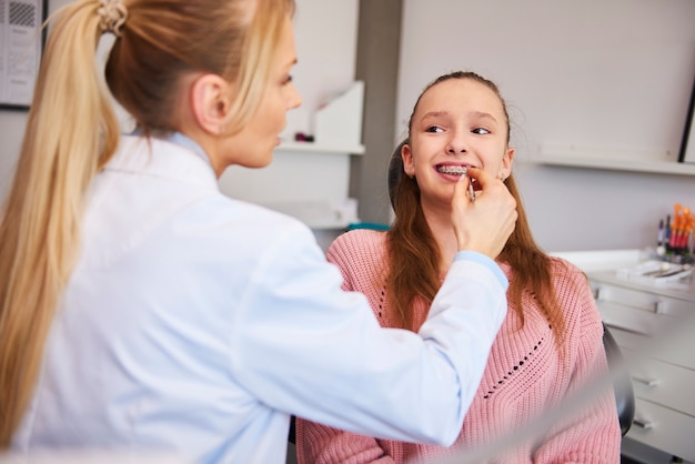 Jovem ortodontista verificando paciente no consultório dentário