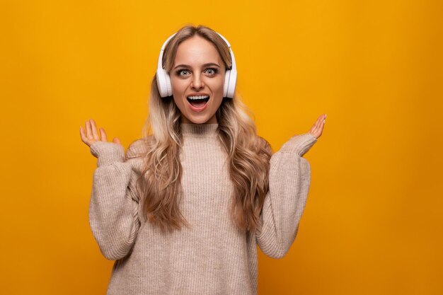 Jovem ouve música e canta junto com fones de ouvido em um fundo amarelo