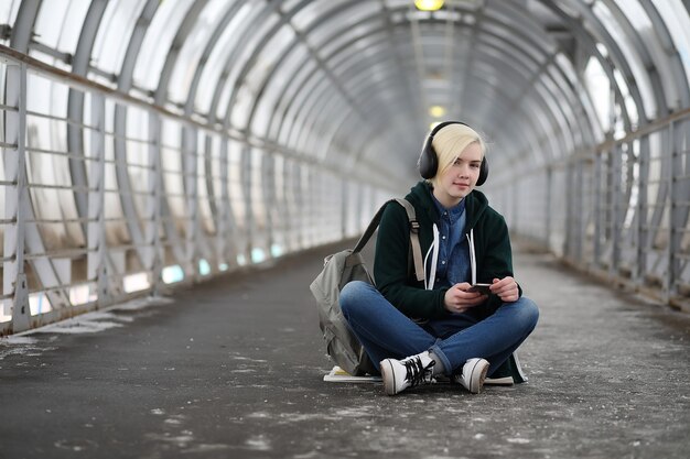 Jovem ouve música em grandes fones de ouvido no túnel do metrô