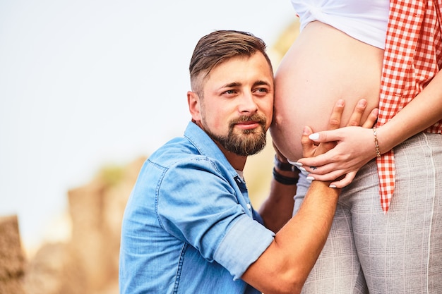 Jovem ouvindo a barriga da mulher grávida