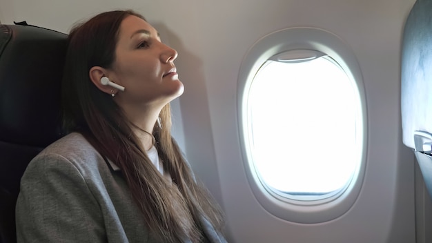 Jovem ouvindo música com fones de ouvido sem fio em um avião