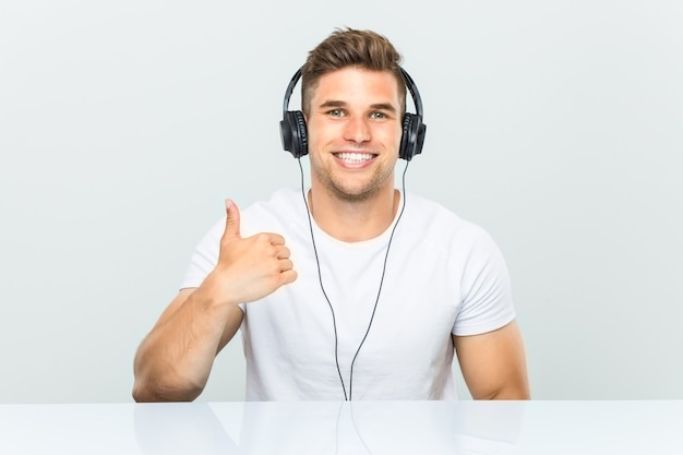 Jovem ouvindo música com fones de ouvido, sorrindo e levantando o polegar