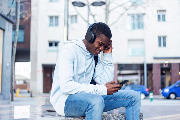 Jovem ouvindo música enquanto usa telefone fora do edifício