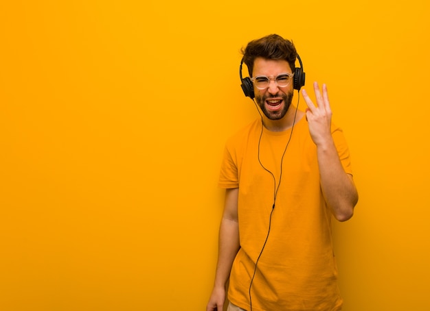 Jovem ouvindo música mostrando o número três