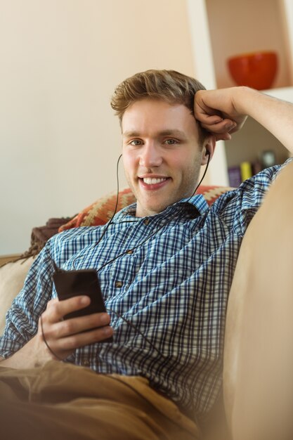 Jovem, ouvindo música no sofá