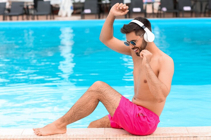 Foto jovem ouvindo música perto da piscina