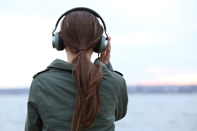 Jovem ouvindo música perto do rio