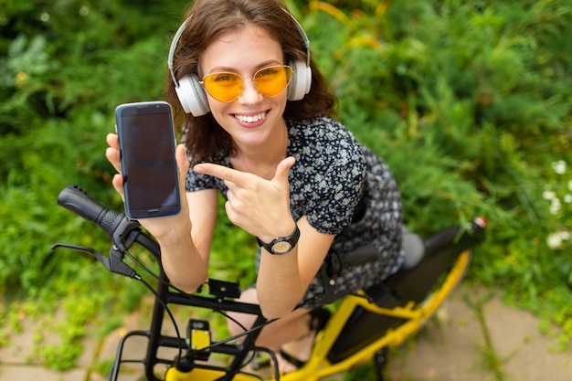 Jovem, ouvir música e andar de bicicleta no parque com um ótimo humor