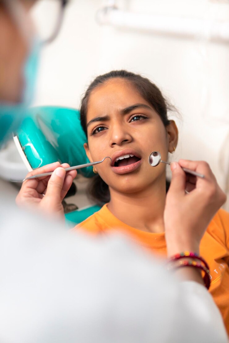Foto jovem paciente indiana sentada em uma cadeira com a boca aberta e o dentista examinando seus dentes com equipamentos dentários na clínica