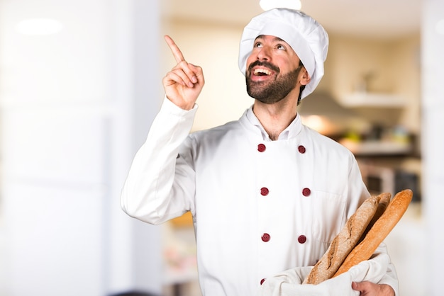 Jovem padaria segurando pão e pensando na cozinha