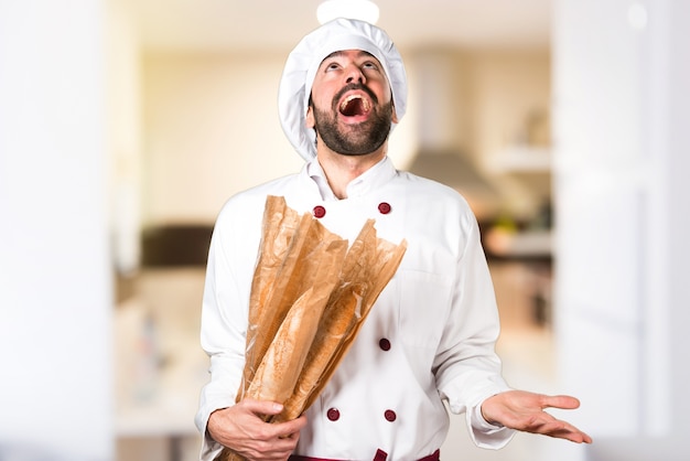 Jovem padaria segurando um pouco de pão e implorando na cozinha