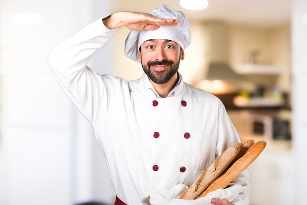 Jovem padaria segurando um pouco de pão e mostrando algo na cozinha