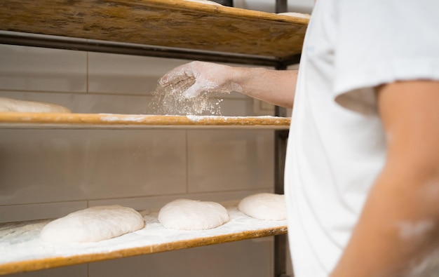 Jovem padeiro coloca pizza em tábuas de madeira para subir e depois de assá-la padaria tradicional de massa