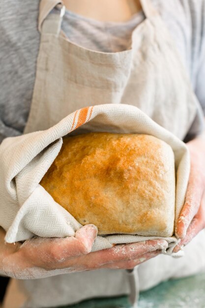 Jovem padeiro segurando pão fermento fresco artesanal.