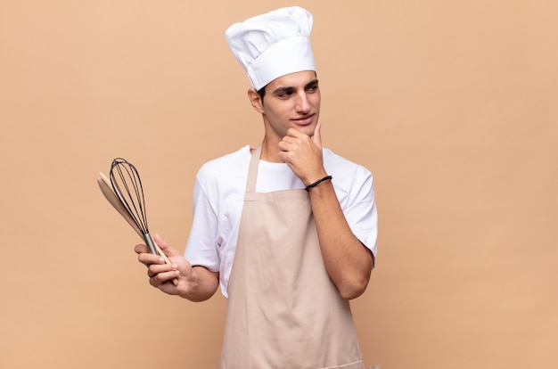 Jovem padeiro sorrindo com uma expressão feliz e confiante com a mão no queixo, pensando e olhando para o lado