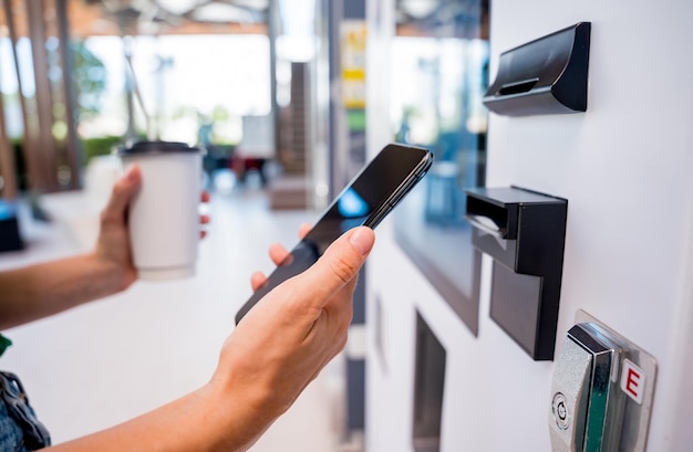 Jovem pagando café em uma máquina de venda automática usando método de pagamento sem contato