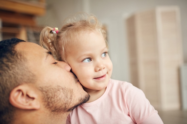 Jovem pai beijando a filha pequena