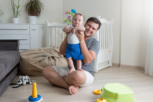 Jovem pai brincando com seu bebê na sala de estar