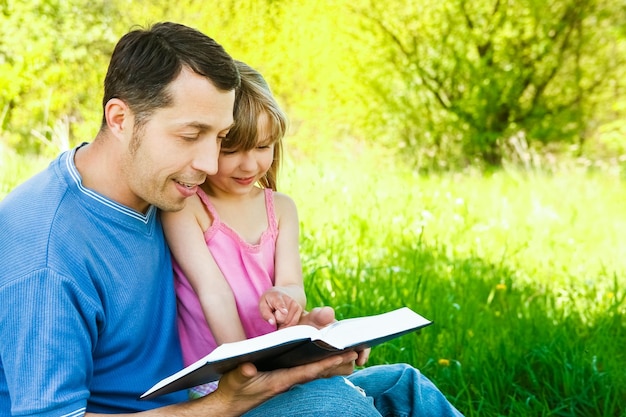 Jovem pai com uma filha pequena lendo a Bíblia