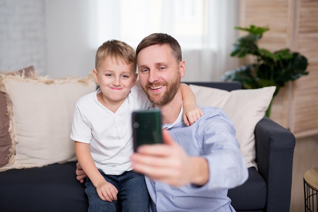 Jovem pai e filho tirando foto de selfie com smartphone em casa