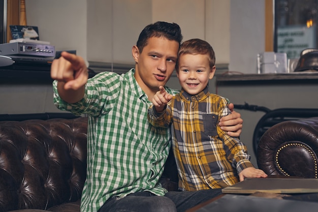 Foto jovem pai e seu filho estiloso na barbearia na sala de espera