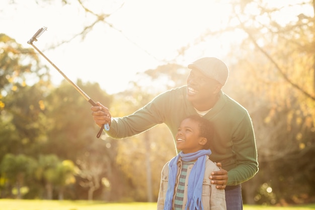 Jovem pai e seu filho tomando selfies em um dia de outono