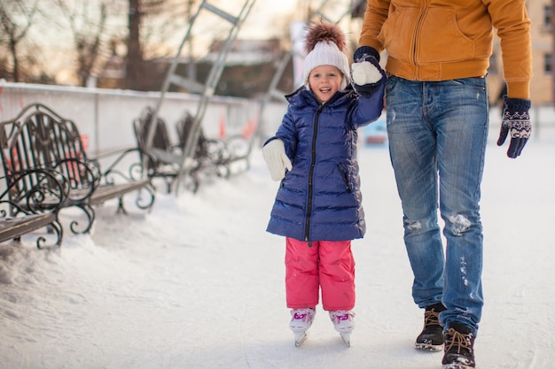 Jovem pai ensinando sua filha a patinar na pista