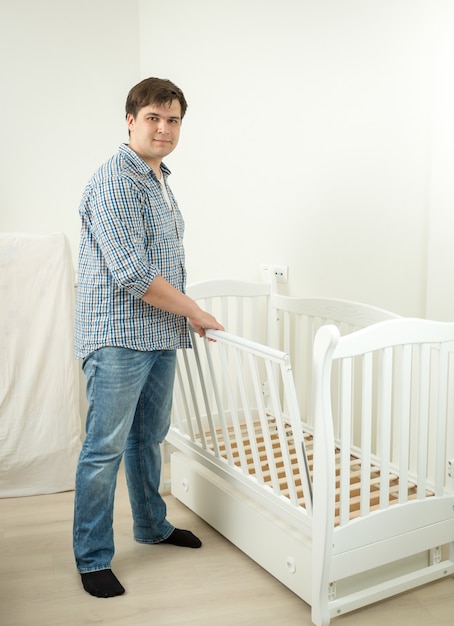 Foto jovem pai expectante montando cama para seu futuro bebê