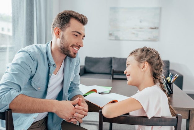 Jovem pai fazendo lição de casa com filha pequena