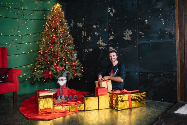 Jovem pai lindo com o filho bonito perto da árvore de Natal com presentes. feliz Natal